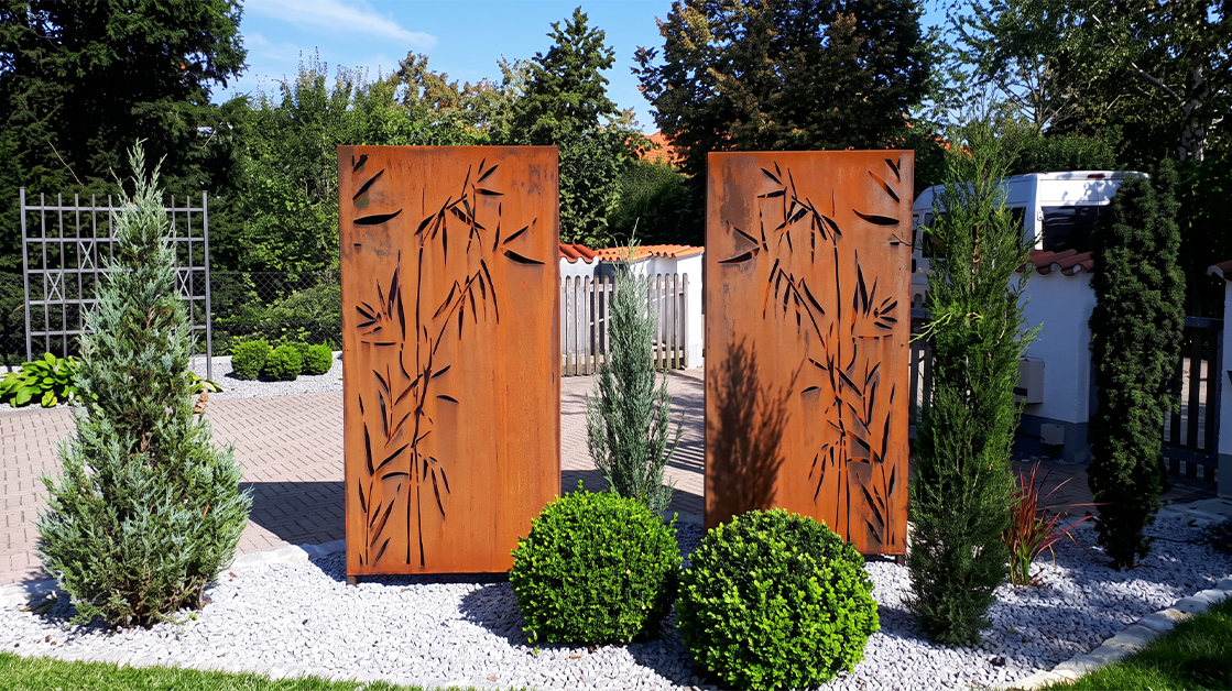 Deux claustras brise-vue en acier Corten découpés de motifs de bambou, installés dans un jardin paysager contemporain.
