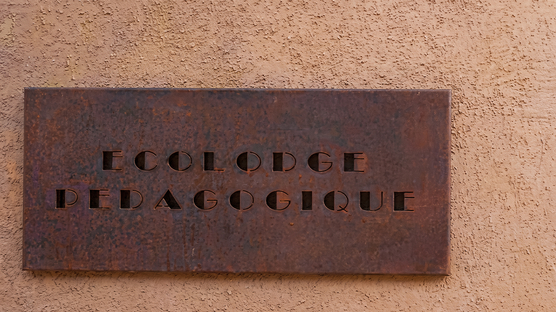 Plaque signalétique murale en acier Corten avec lettrage découpé, conçue sur mesure pour identifier un établissement.
