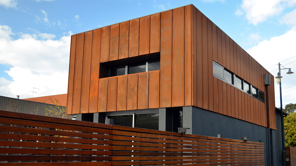 Bâtiment contemporain habillé d’un bardage vertical en acier Corten, conçu sur mesure pour créer une façade architecturale durable et auto-patinable.