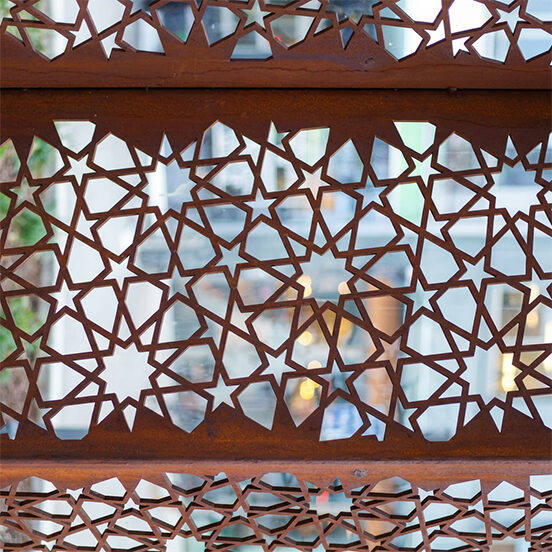 Détail d’un moucharabieh en acier Corten découpé de motifs géométriques, utilisé comme élément décoratif et brise-soleil architectural.