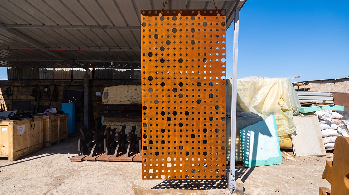 Panneau architectural en acier Corten perforé de motifs circulaires, fabriqué sur mesure dans un atelier métallique au Maroc.