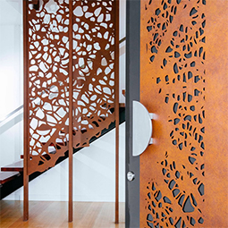 Porte et claustra en acier Corten découpés au laser avec un motif organique inspiré des feuilles.
