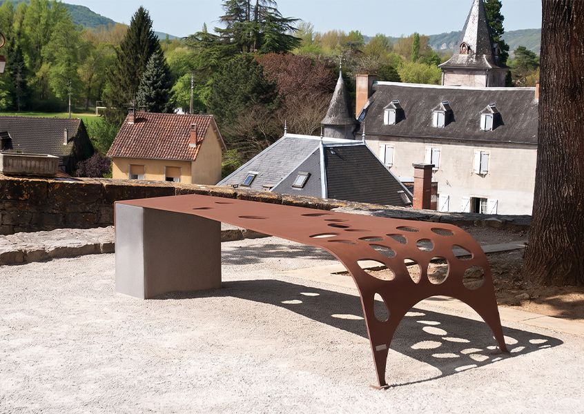 Banc sculptural en acier Corten perforé, associé à un support minéral dans un espace extérieur paysager.