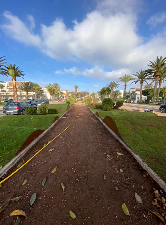 Bordure droite en acier Corten séparant nettement une allée dallée d’un massif végétalisé et paillé.