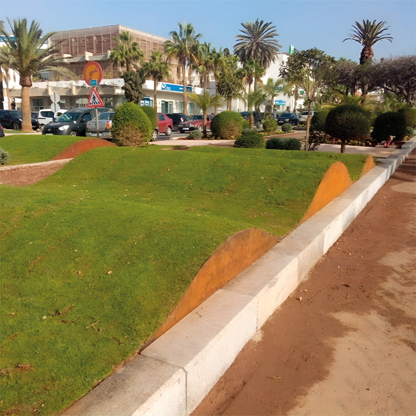 Bordures courbes en acier Corten délimitant des reliefs engazonnés dans un aménagement paysager urbain au Maroc.