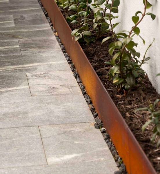 Bordures linéaires en acier Corten structurant une allée et des espaces engazonnés dans un aménagement paysager urbain.