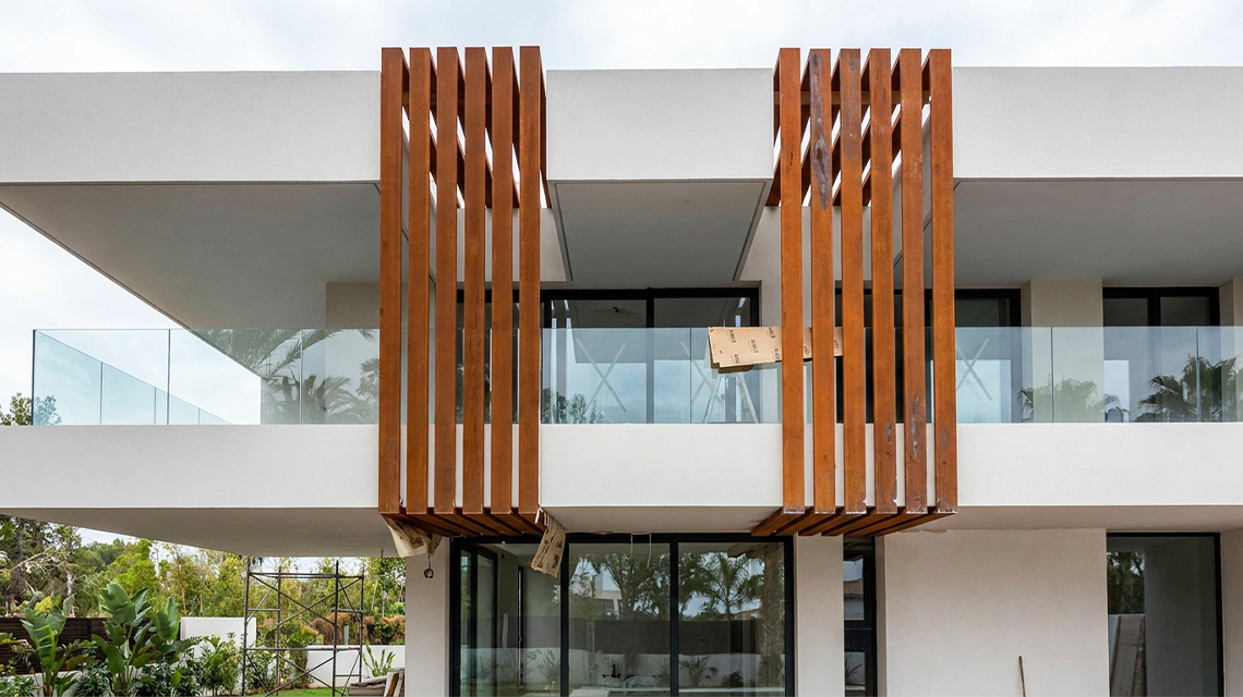 Lames verticales en acier Corten installées devant les balcons d’une villa contemporaine comme brise-soleil architectural.