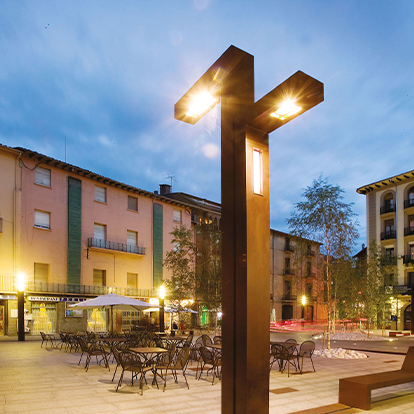 Luminaire urbain contemporain en acier Corten équipé de plusieurs sources lumineuses dans un espace public aménagé.
