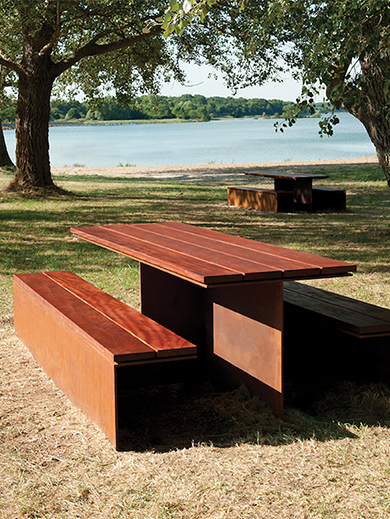 Table et banc en acier Corten avec plateau en bois installés dans un espace naturel pour un aménagement extérieur élégant et durable.